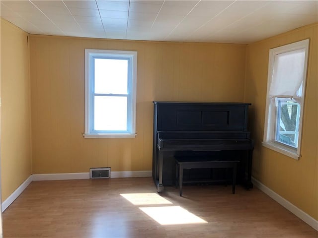 living area with light wood-style flooring, visible vents, and baseboards