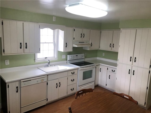 kitchen featuring light countertops, a sink, wood finished floors, white appliances, and under cabinet range hood