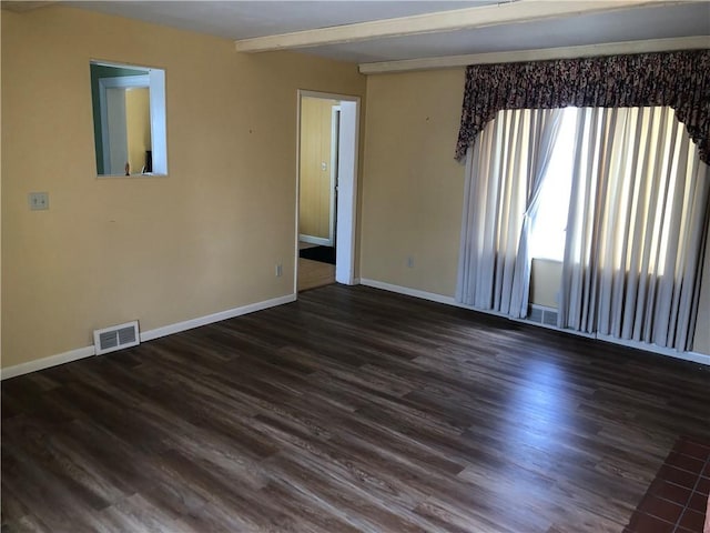 spare room featuring baseboards, visible vents, dark wood-type flooring, and beamed ceiling