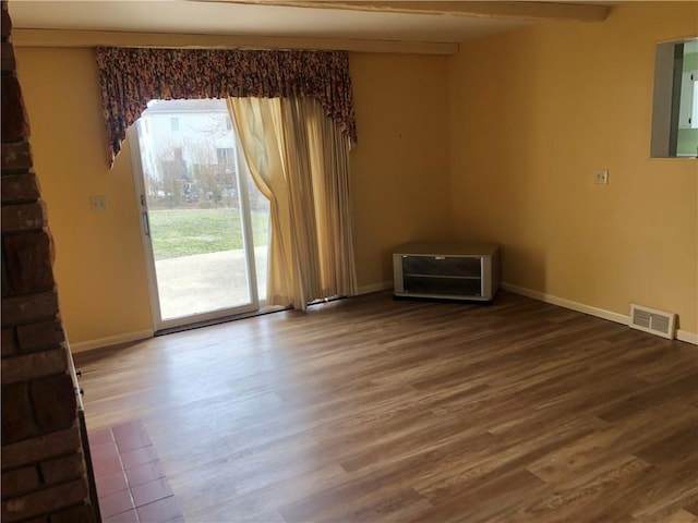 unfurnished room featuring visible vents, baseboards, and wood finished floors