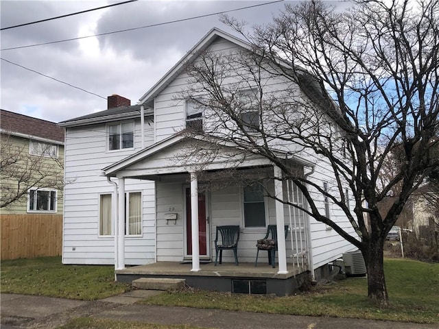 view of front of property with a porch, central AC, fence, a chimney, and a front yard