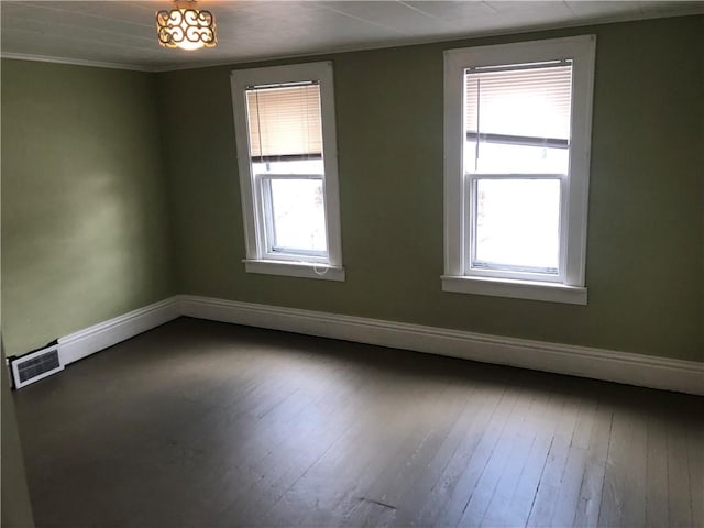 unfurnished room with dark wood-type flooring, visible vents, and baseboards