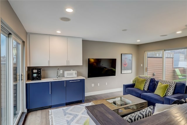 living room with light wood finished floors, recessed lighting, and baseboards