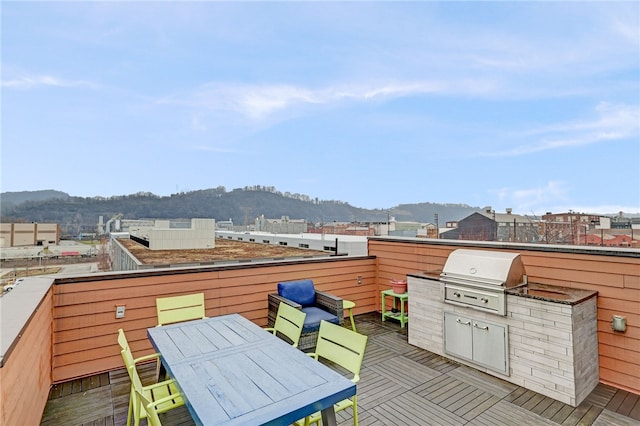 wooden deck featuring outdoor dining space, a mountain view, and area for grilling