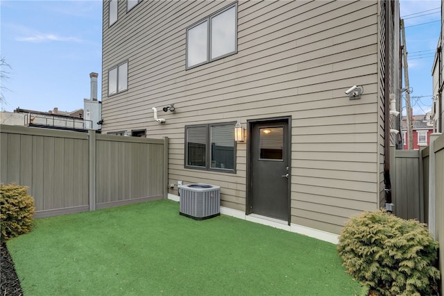 back of house featuring central AC, a yard, and a fenced backyard