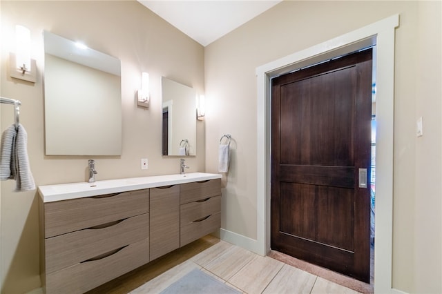 bathroom with double vanity, a sink, and baseboards