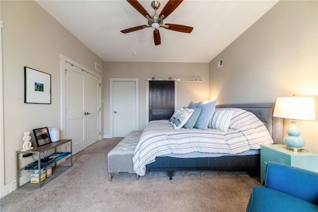 bedroom with carpet floors, a barn door, visible vents, and a ceiling fan