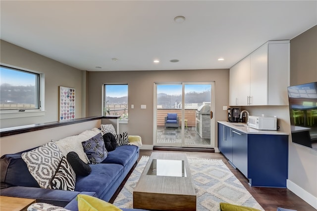 living area with baseboards, dark wood-type flooring, and recessed lighting