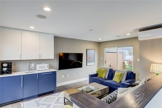 living room featuring light wood-type flooring, an AC wall unit, baseboards, and recessed lighting