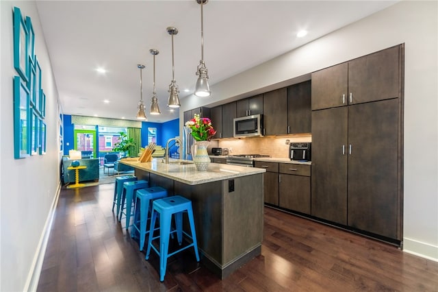 kitchen with dark wood-style floors, stainless steel appliances, a breakfast bar area, and a sink