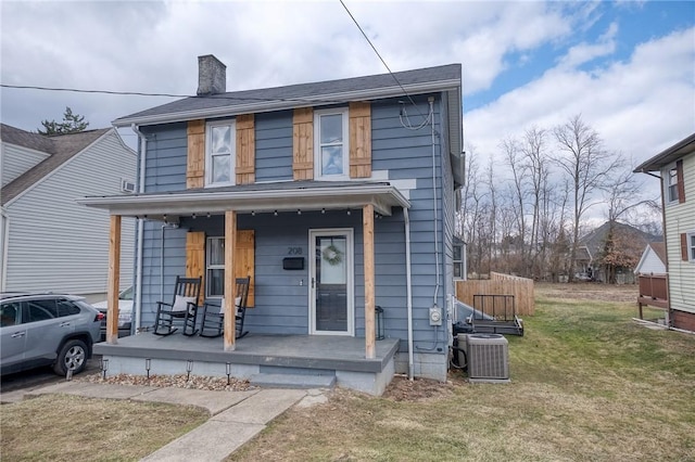 traditional style home featuring covered porch, a chimney, a front yard, and central air condition unit