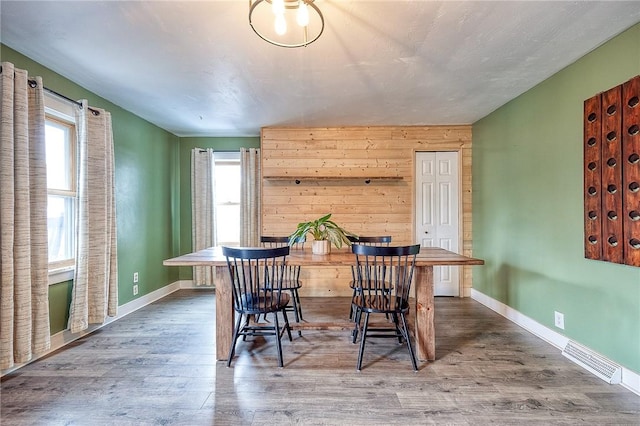 dining room featuring baseboards, wood finished floors, visible vents, and a healthy amount of sunlight