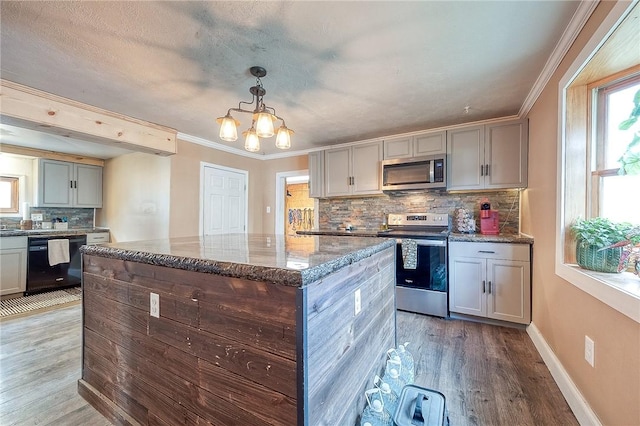 kitchen with appliances with stainless steel finishes, plenty of natural light, light wood-style flooring, and dark stone countertops