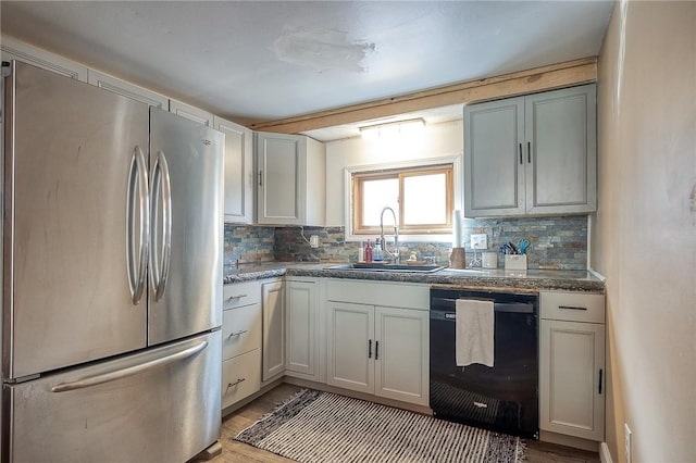 kitchen with decorative backsplash, freestanding refrigerator, dishwasher, and a sink