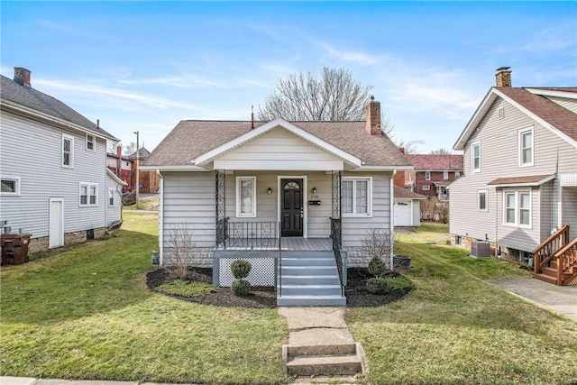 bungalow with a shingled roof, a front yard, covered porch, and central AC