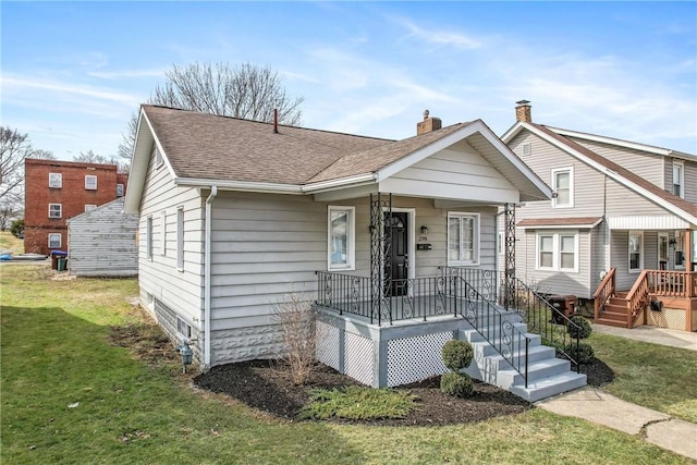 view of front of home featuring covered porch, a front lawn, a chimney, and a shingled roof