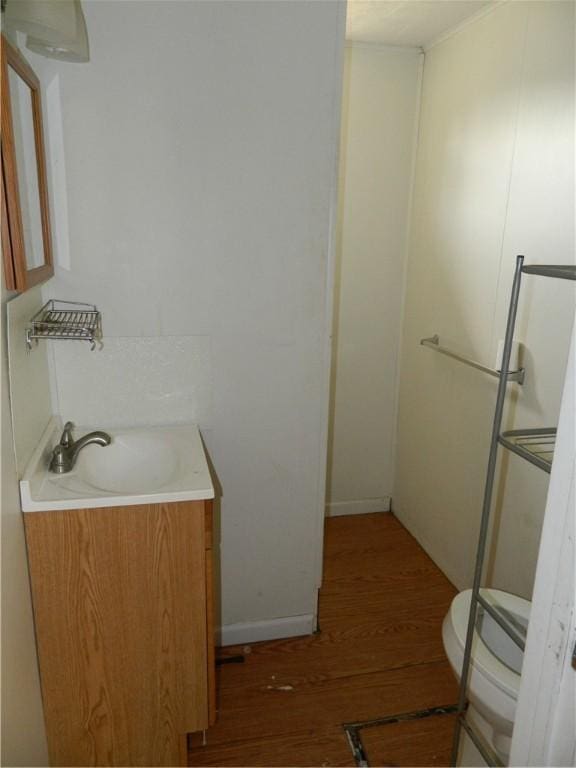 bathroom with toilet, wood finished floors, and vanity