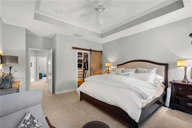 bedroom featuring a raised ceiling, visible vents, a barn door, light carpet, and baseboards