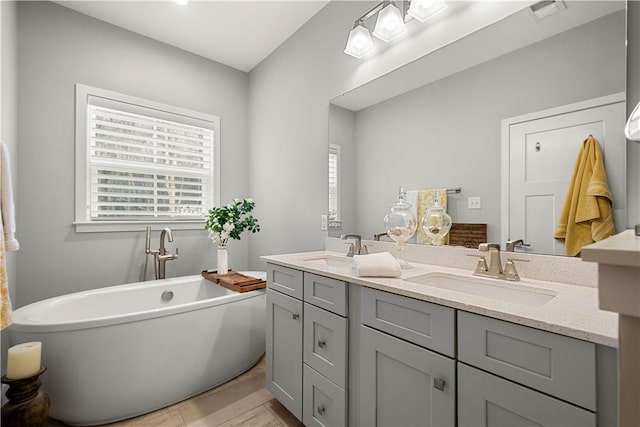 full bath with a soaking tub, plenty of natural light, and a sink