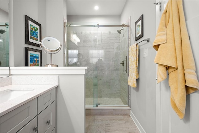 full bathroom with a stall shower, vanity, and baseboards