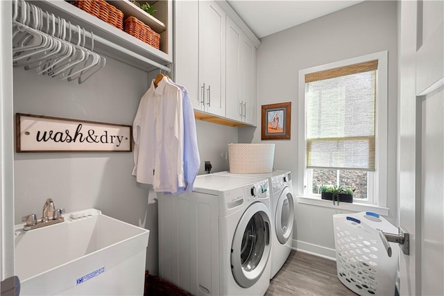 laundry room featuring cabinet space, baseboards, washer and clothes dryer, wood finished floors, and a sink