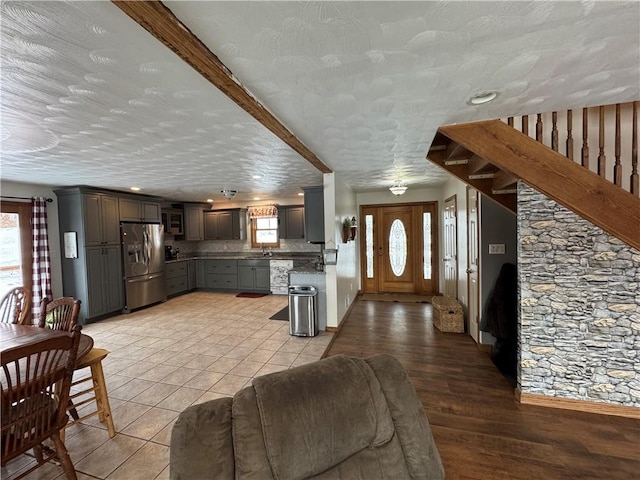 unfurnished living room featuring stairs, light tile patterned floors, and a sink