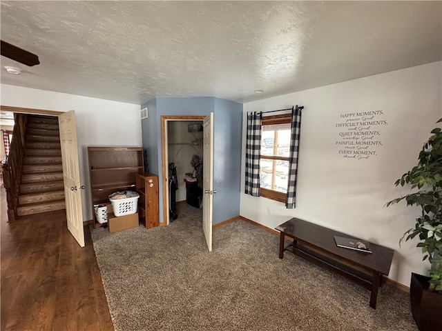 bedroom featuring a spacious closet, a textured ceiling, and baseboards