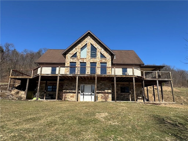 rear view of property featuring stone siding, a wooden deck, a yard, and a shingled roof