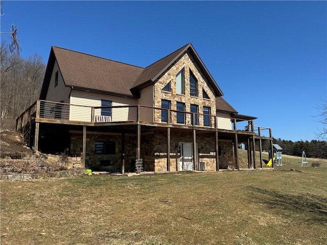 rear view of property with a yard, stone siding, and a deck