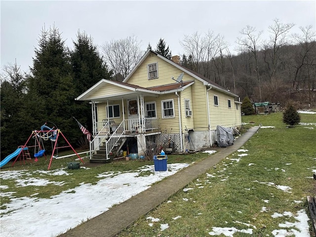 bungalow-style home with a porch, a playground, and a front lawn