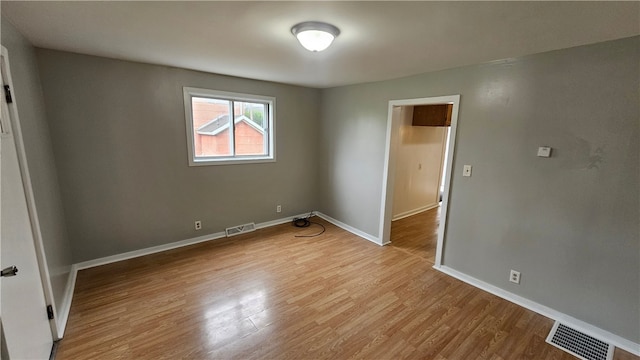 unfurnished room featuring light wood-type flooring, baseboards, and visible vents