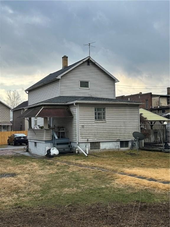 back of house with a chimney and a shingled roof