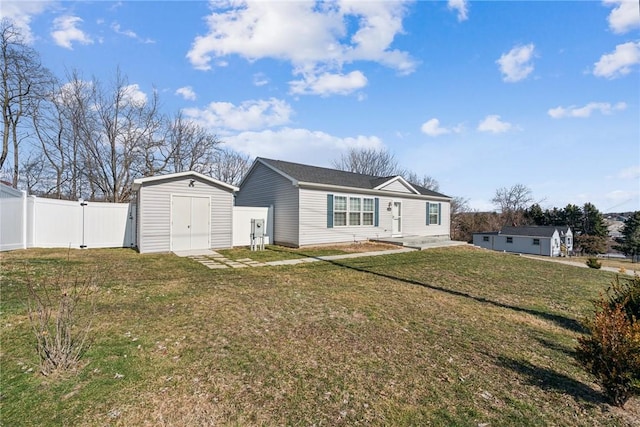 view of front of house featuring a front lawn, an outbuilding, fence, and a storage shed