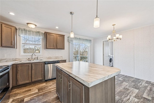 kitchen with washer / clothes dryer, black electric range oven, stainless steel dishwasher, a sink, and plenty of natural light