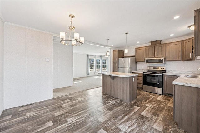 kitchen with dark wood finished floors, a center island, light countertops, stainless steel appliances, and a sink