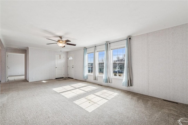 empty room featuring carpet floors, visible vents, and a ceiling fan