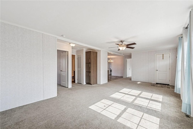 spare room with ceiling fan with notable chandelier, crown molding, and light colored carpet