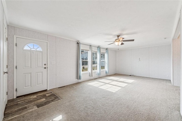 foyer entrance featuring ceiling fan, carpet floors, and crown molding