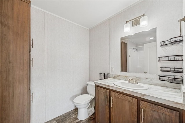 bathroom featuring toilet, wood finished floors, vanity, walk in shower, and crown molding