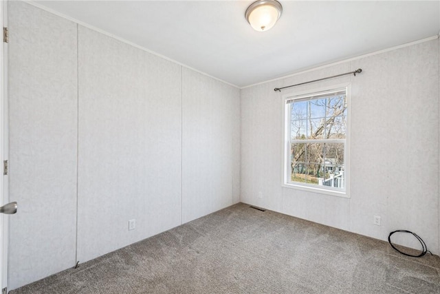 spare room featuring ornamental molding, carpet flooring, and visible vents