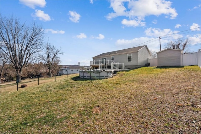 back of property with an outbuilding, a lawn, fence, and a covered pool