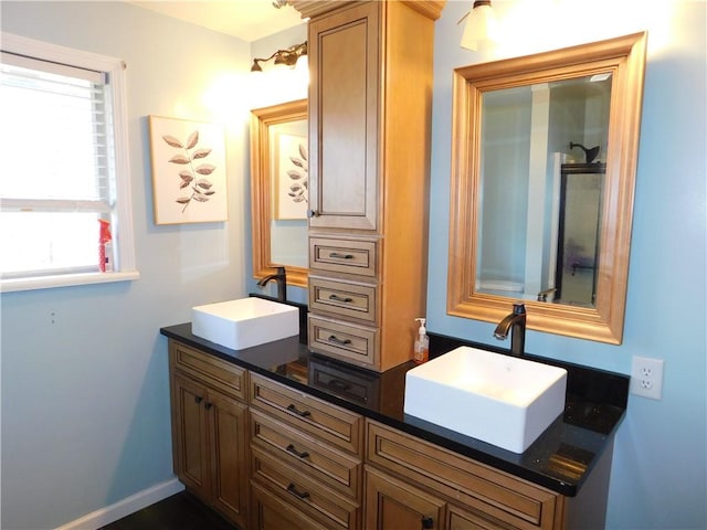 bathroom featuring a sink, baseboards, and double vanity