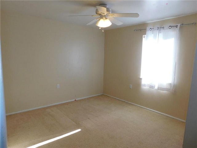 carpeted empty room with a ceiling fan, a wealth of natural light, and baseboards