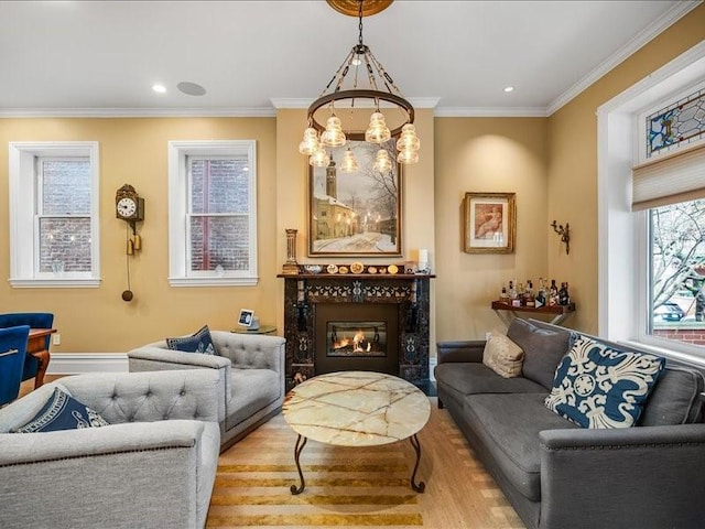 sitting room with wood finished floors, an inviting chandelier, a glass covered fireplace, and crown molding