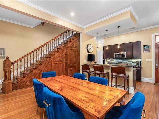 dining area with baseboards, light wood finished floors, stairway, and crown molding