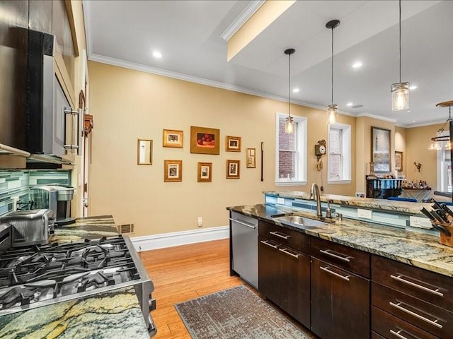 kitchen featuring appliances with stainless steel finishes, light wood-style floors, crown molding, and a sink