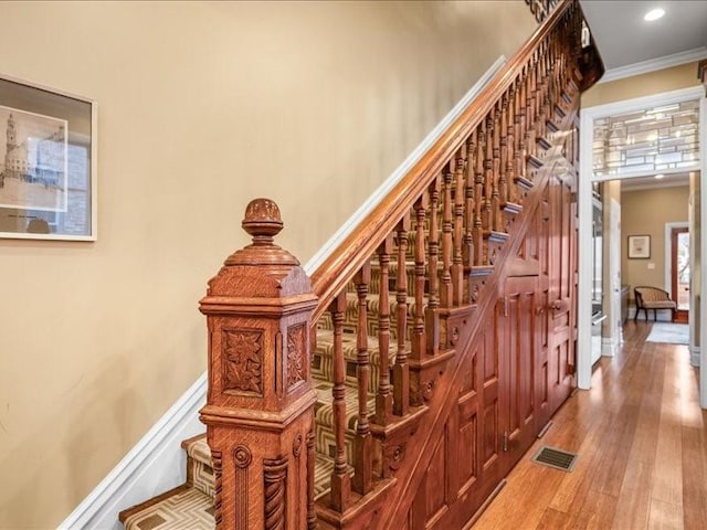 staircase featuring recessed lighting, wood finished floors, visible vents, baseboards, and crown molding