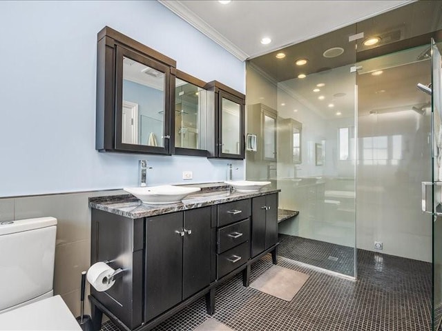 full bath with toilet, a shower stall, ornamental molding, and a sink