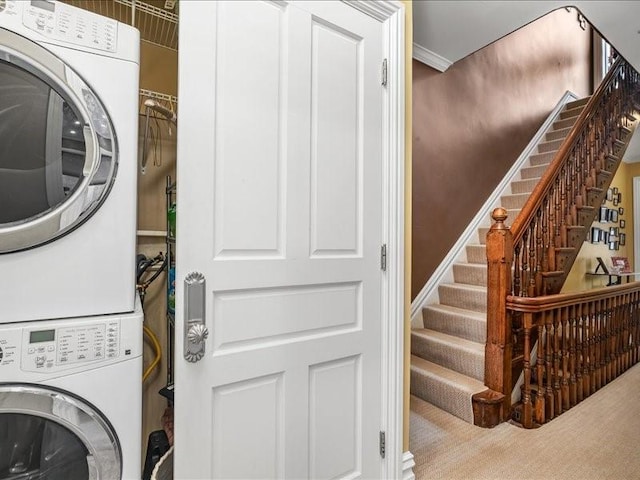 clothes washing area with carpet, stacked washer and clothes dryer, and laundry area