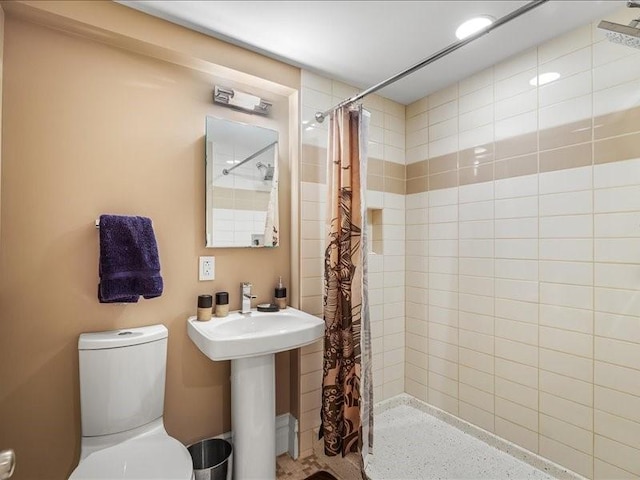 bathroom featuring toilet and a tile shower